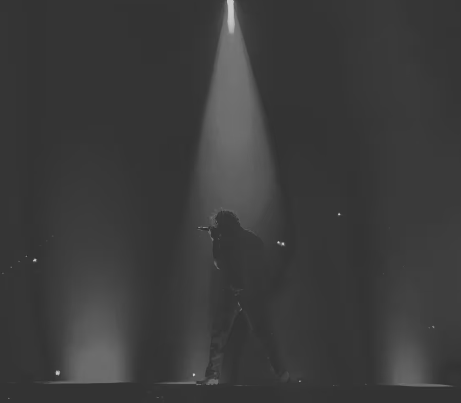 Artist performing under a single spotlight on a darkened stage